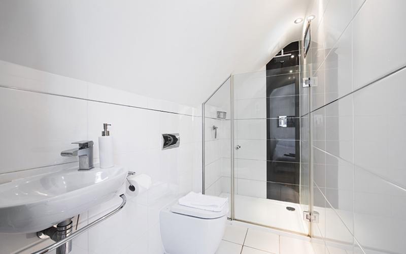 Modern white bathroom with walk-in shower, toilet, and wall-mounted sink