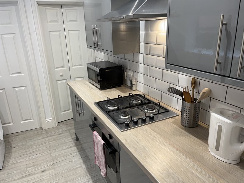 Modern kitchen with gas hob, white subway tile backsplash, stainless steel appliances and wooden countertop