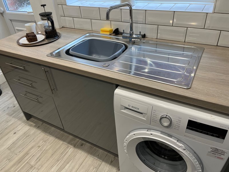 Modern kitchen with sink, tap, subway tile backsplash, and integrated washing machine