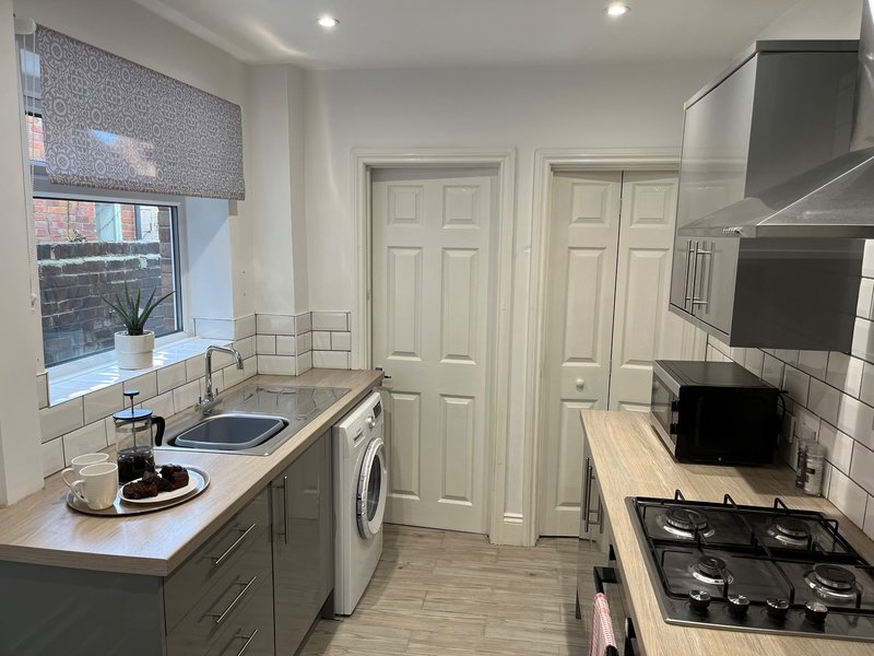 Modern kitchen with grey cabinetry, white subway tiles, washing machine and gas cooktop