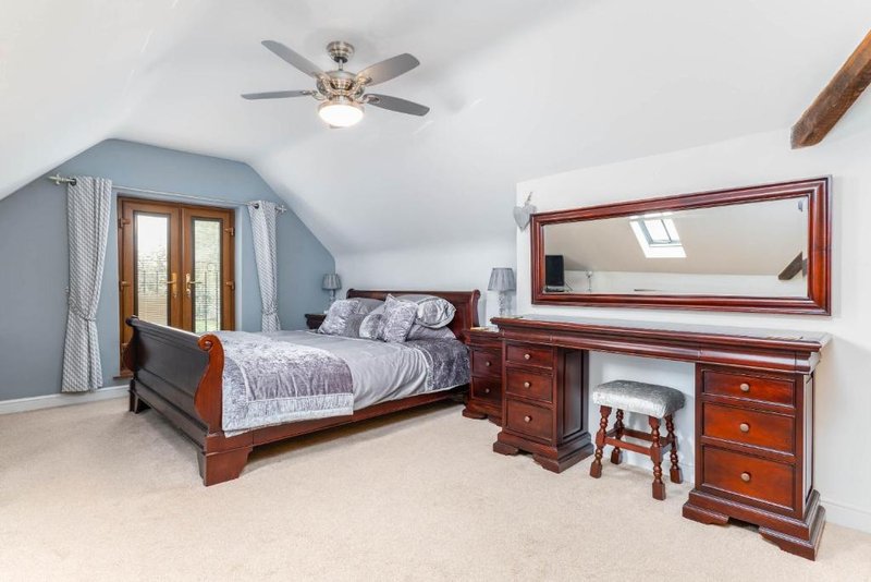 Master bedroom, superking-sized bed with wooden bed, dresser, mirror, ceiling fan and blue accent wall