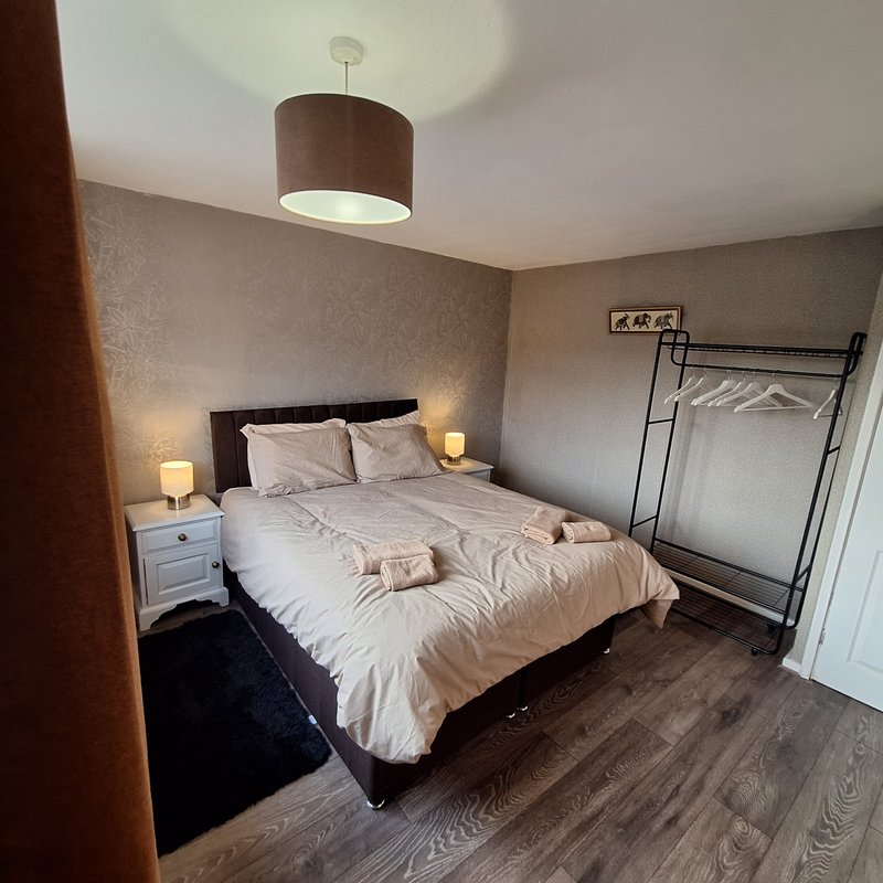 Bedroom with double bed, bedside lamps, clothing rack, and pendant light fixture
