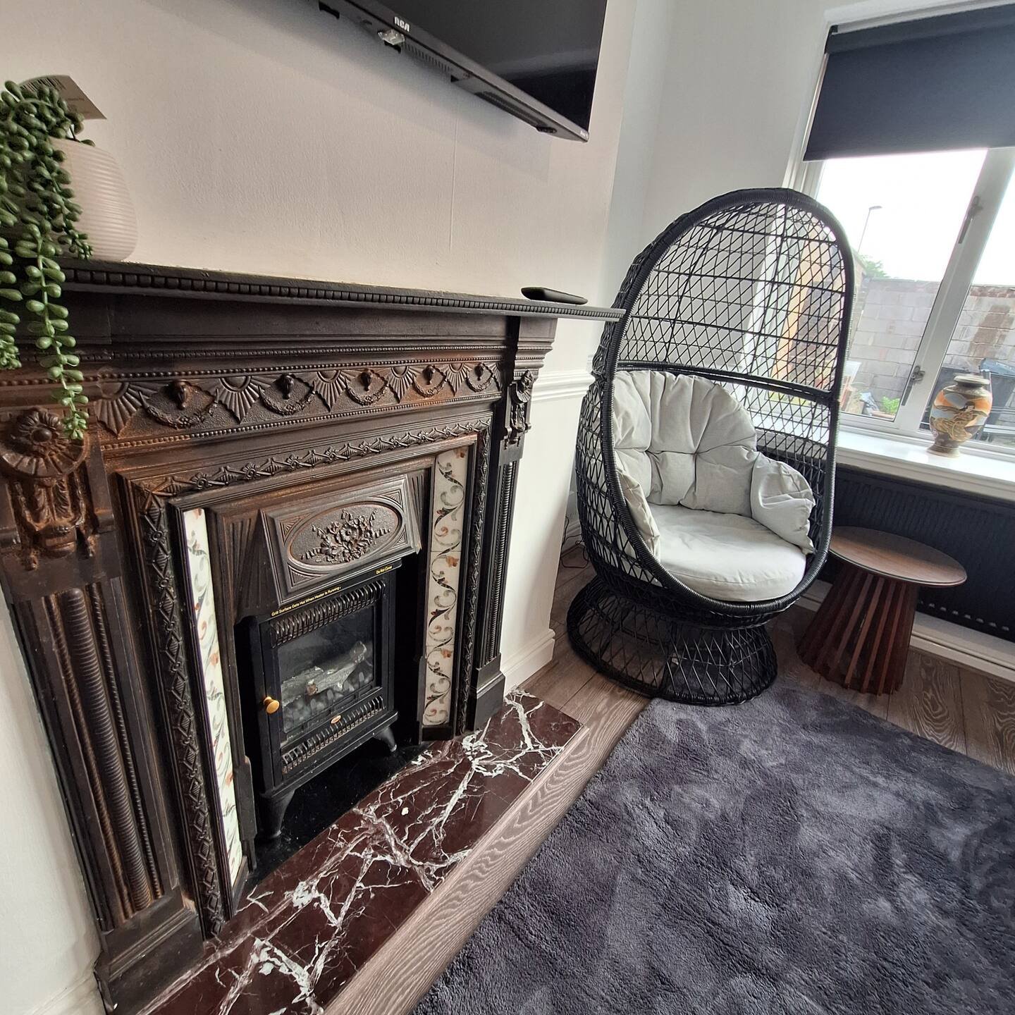 Living room with ornate fireplace, hanging egg chair with cushion, and window seating area