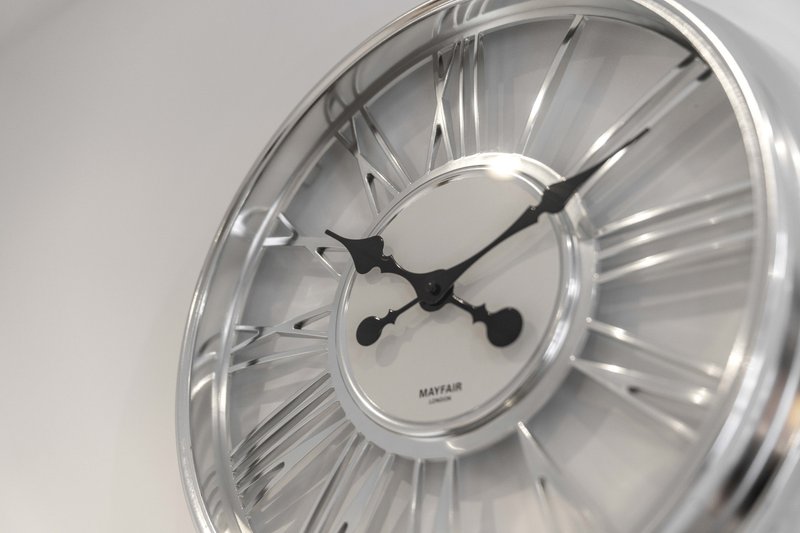 Close-up of modern wall clock with Roman numerals and black hands