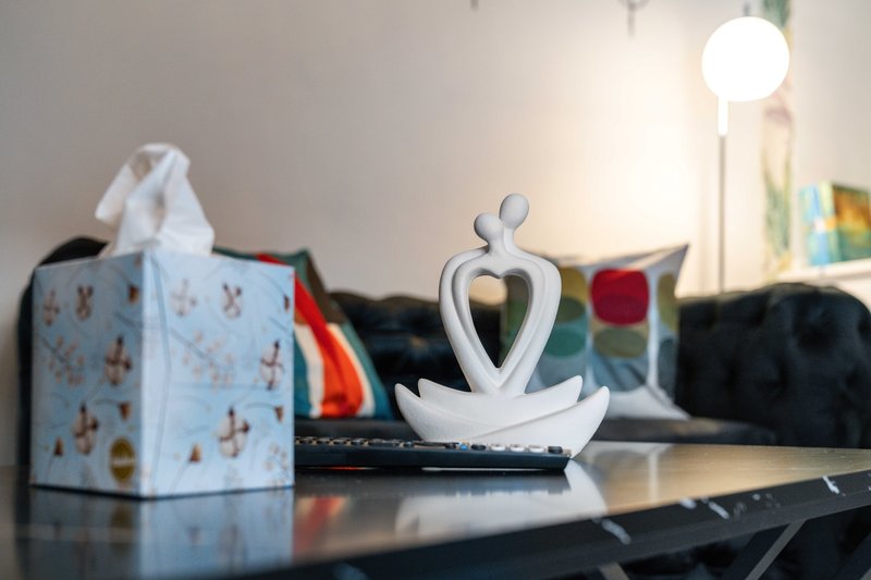 Living room shelf with decorative heart sculpture, tissue box, and lamp in background