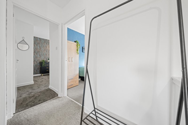 Bright hallway with white doors, grey carpet, and modern framed mirror on wall