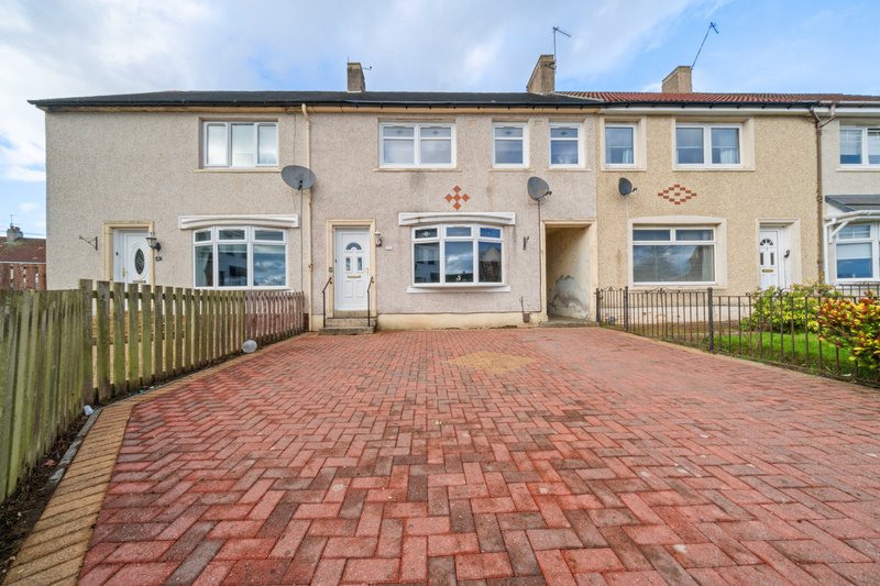 Cream-coloured terraced house with red brick driveway, white-framed windows and wooden fence