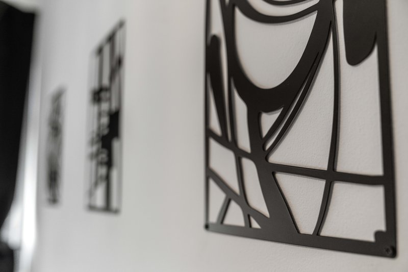 White wall with three pieces of modern abstract black framed artwork