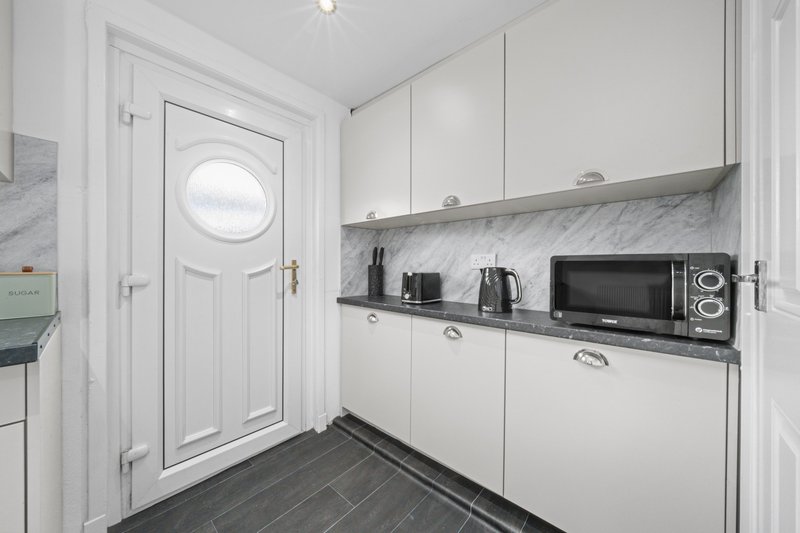 Modern white kitchen with marble countertop, microwave, kettle and appliances