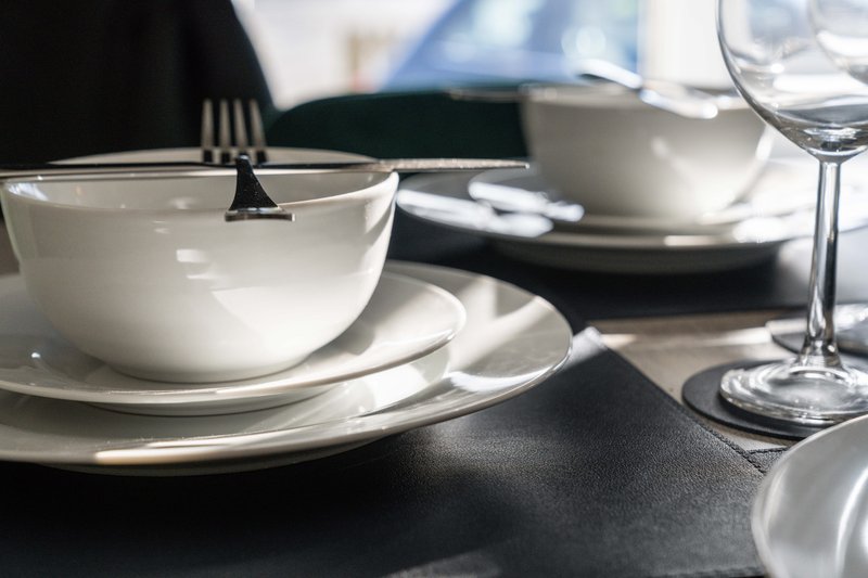 Formal dining table set with white plates, bowls, glasses and cutlery