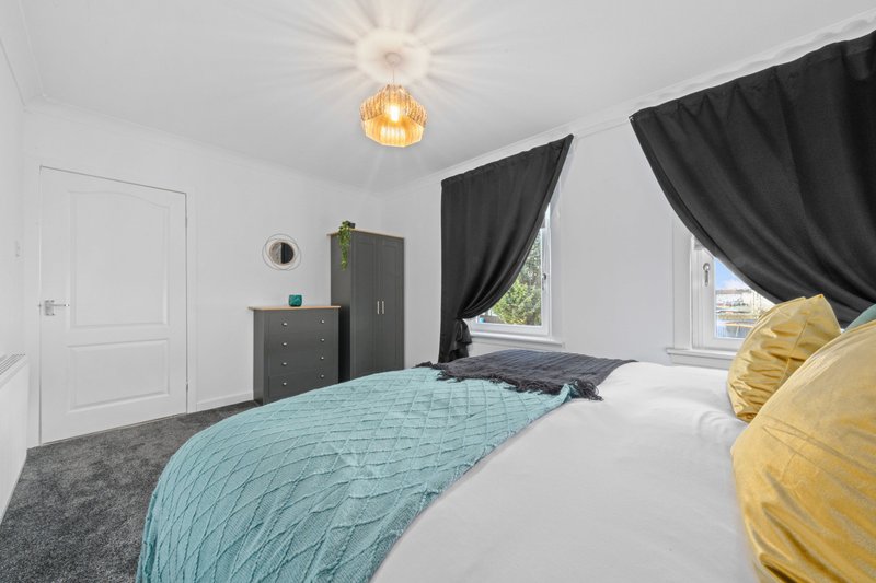 Modern bedroom with double bed, turquoise bedding, yellow cushions, dark furniture and pendant light