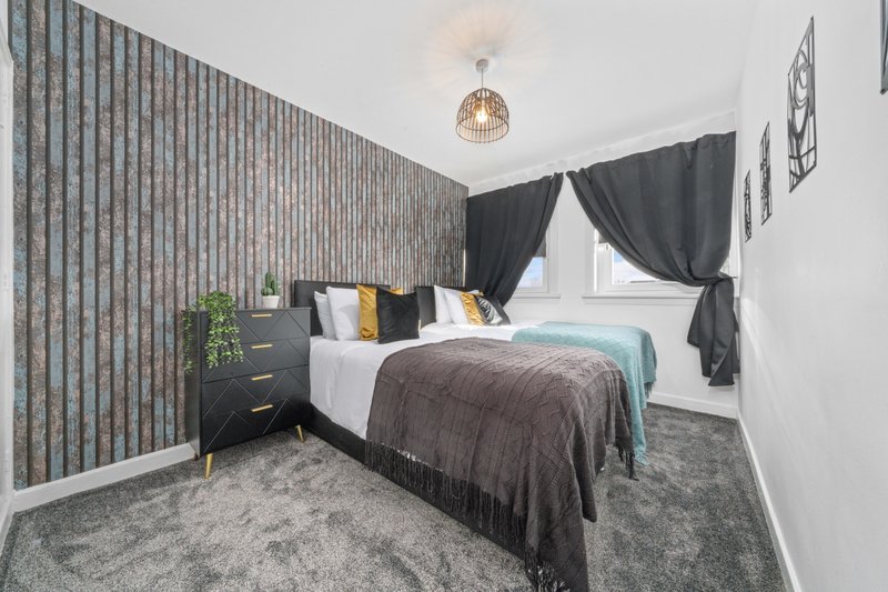 Modern bedroom with double bed, dark headboard, bedside table, and black curtains