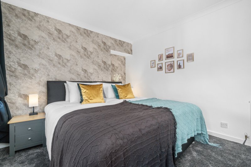 Modern bedroom with double bed, marble headboard, bedside lamp and framed wall art