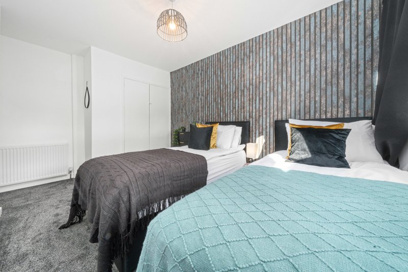 Modern bedroom with two beds, pendant light, striped wallpaper and white wardrobe