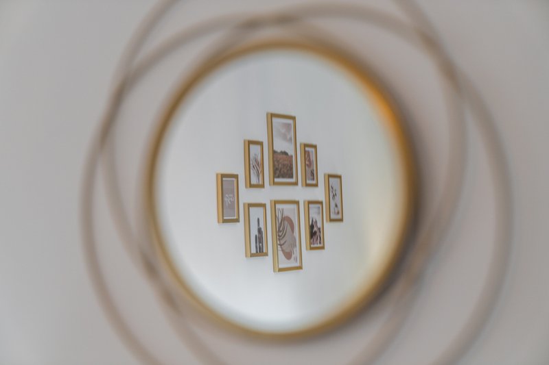 Ceiling with concentric circular plasterwork and framed gallery wall arrangement of small pictures