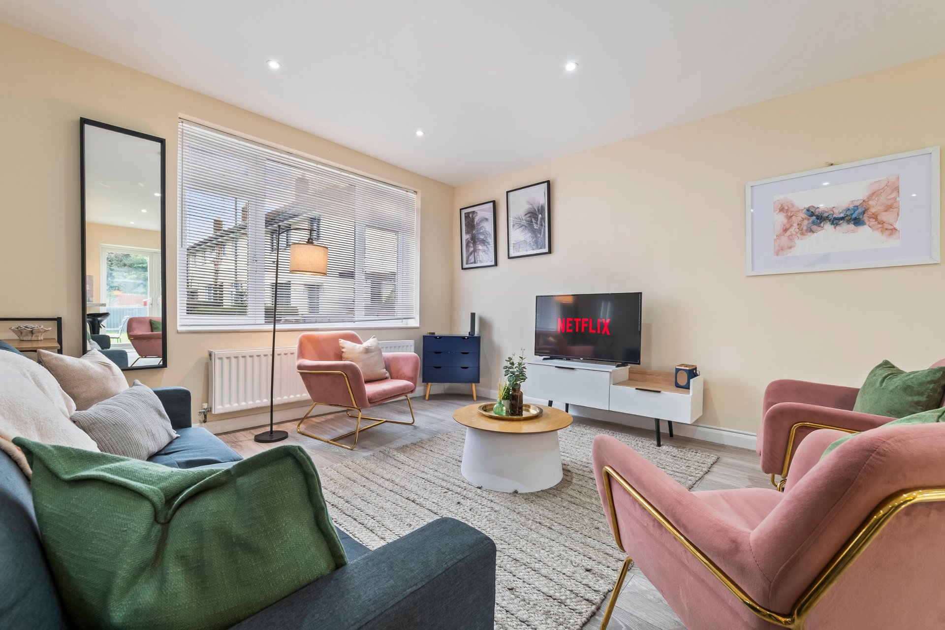 Modern living room with colorful armchairs, TV, coffee table, and large windows