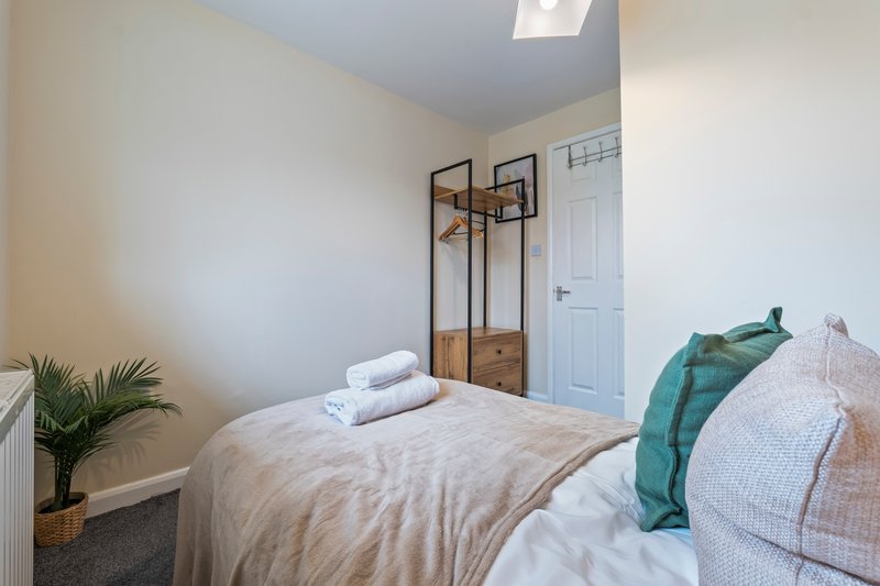 Bright bedroom with double bed, wooden coat stand, potted plant and skylight window