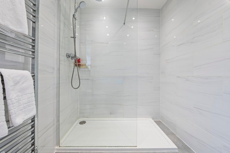 Modern bathroom with walk-in shower, white tile walls, and heated towel rack