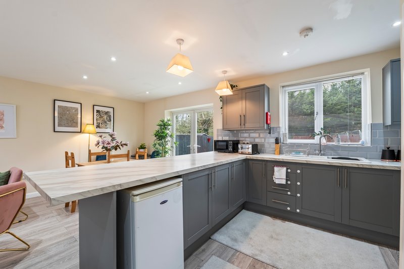 Modern kitchen with dark grey cabinetry, white quartz island, and open-plan living area