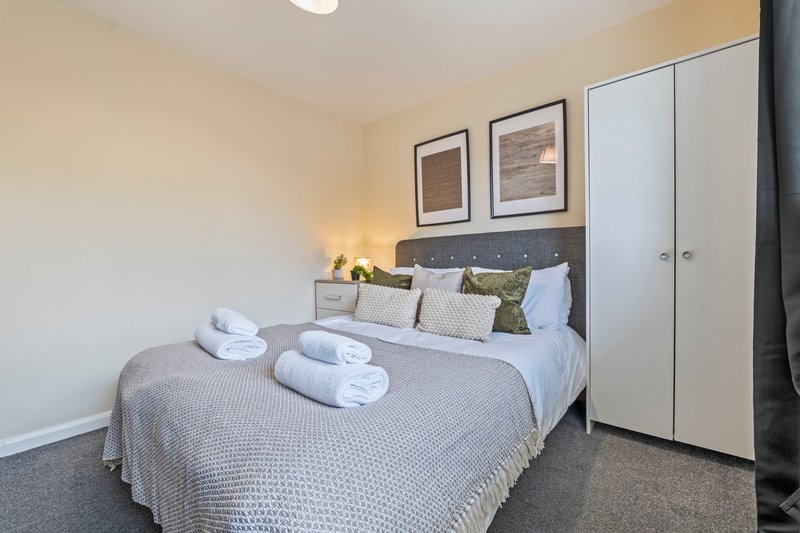 Modern bedroom with double bed, rolled towels, bedside lamps and framed wall art