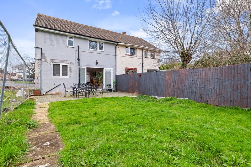 White rendered house with garden, patio area, wooden fence and bare tree