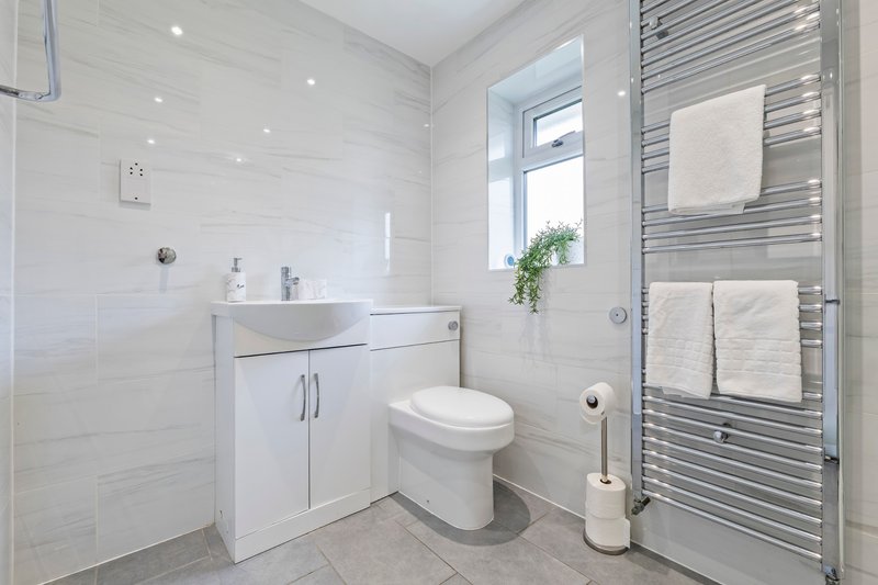 Modern bathroom with white vanity, toilet, heated towel rail and walk-in shower