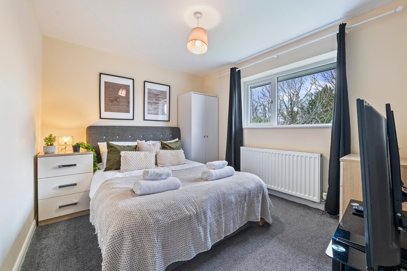 Bright modern bedroom with double bed, white bedside table, framed wall art, and black four-poster frame