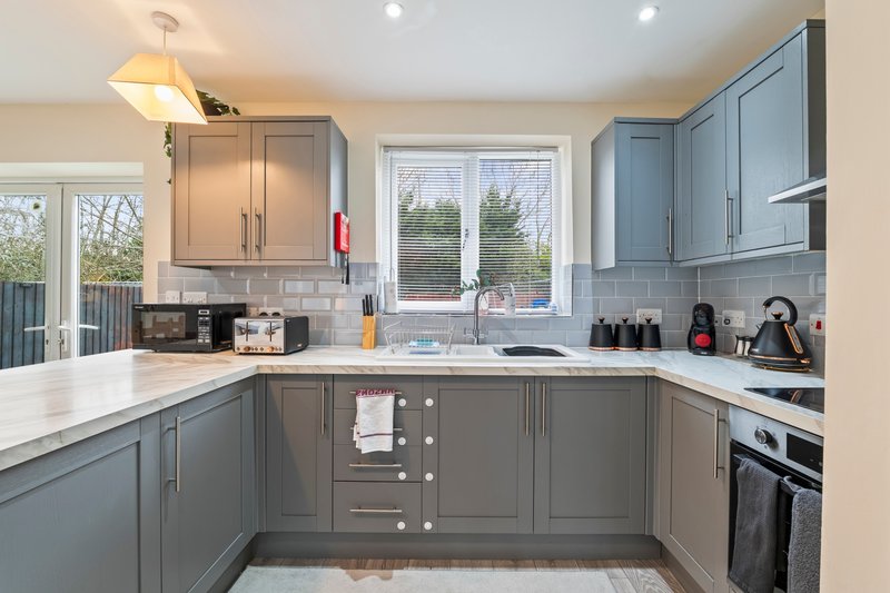 Modern kitchen with grey cabinetry, white countertops, stainless steel appliances and garden view