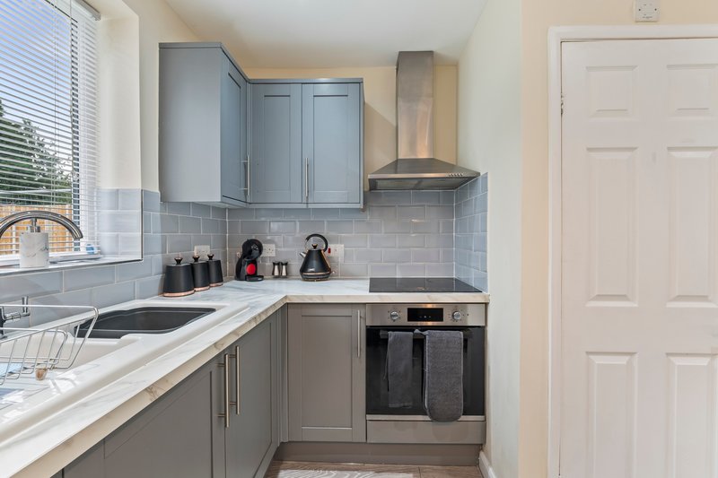 Modern kitchen with grey cabinets, subway tile backsplash, stainless steel appliances and window