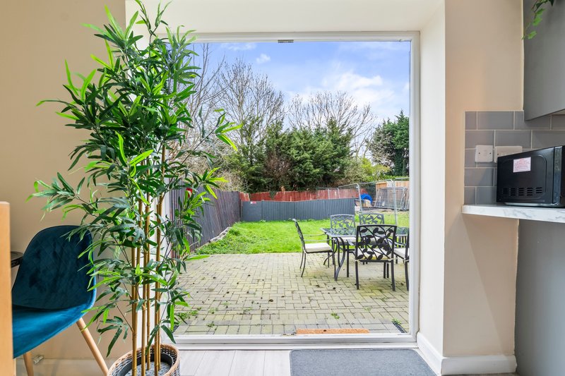 Modern kitchen with patio doors opening to garden with paved seating area and lawn