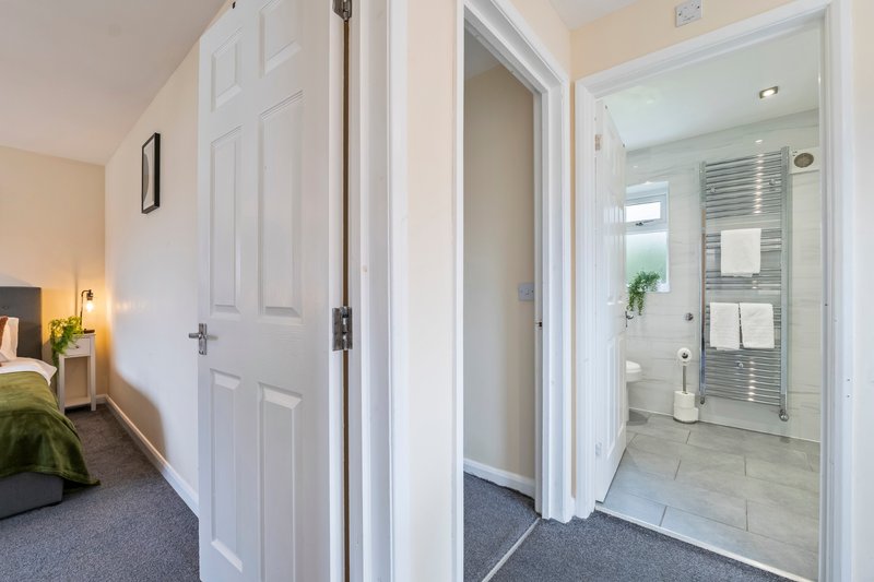 Hallway with open doors leading to bedroom and ensuite bathroom with shower