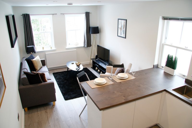 Open-plan living room and kitchen with sofa, dining table, TV unit and windows