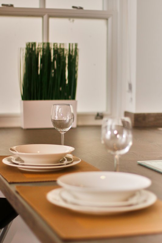 Dining table set with white plates, wine glasses and potted green plant decoration