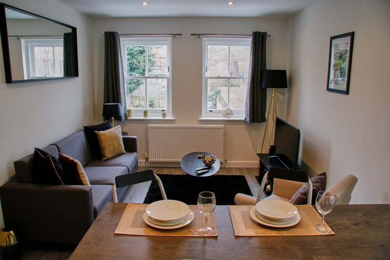 Open-plan living and dining area with seating, dining table set for two, and windows with garden views