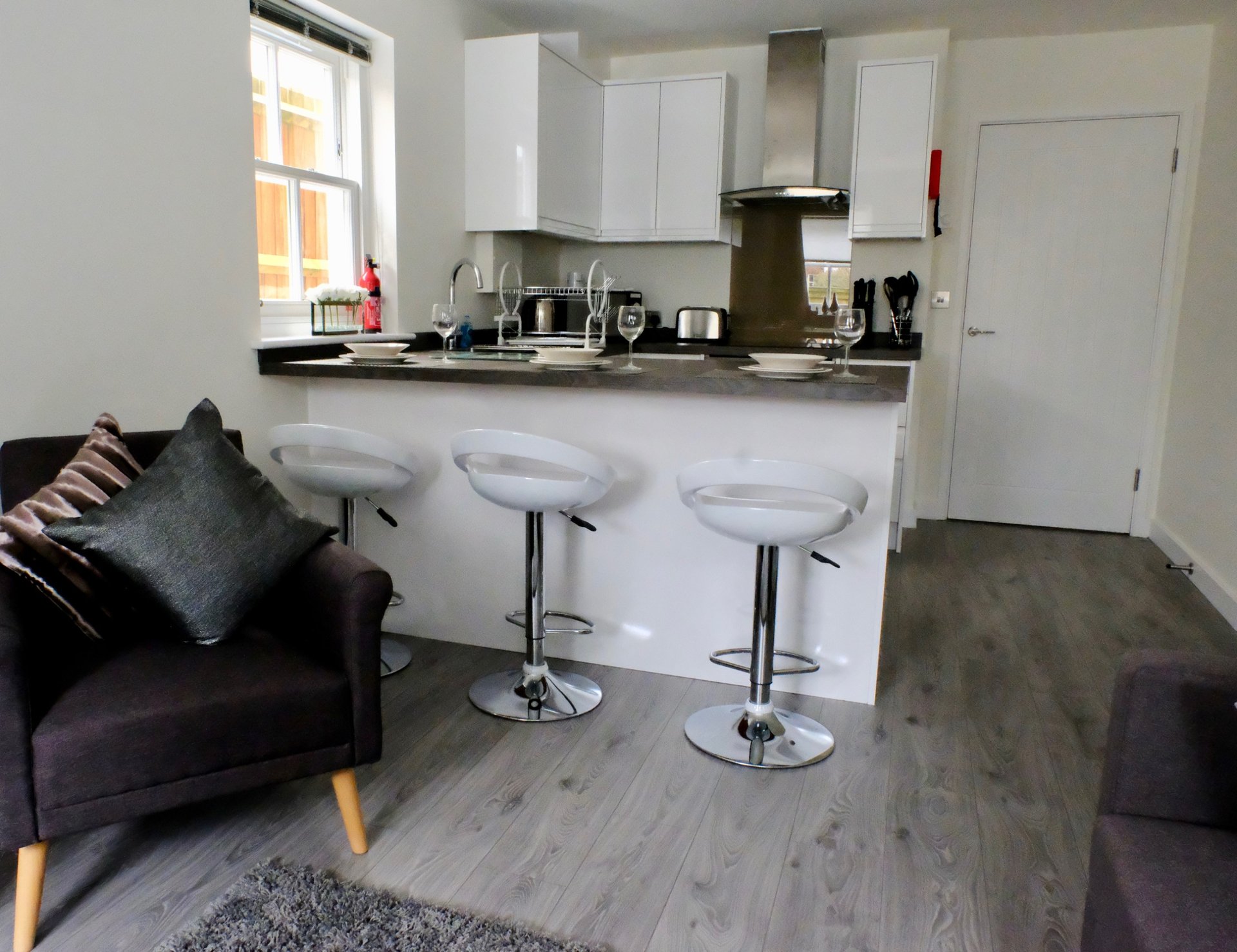 Open-plan kitchen and living area with white cabinetry, breakfast bar, and seating