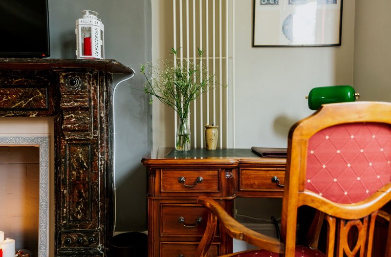 Living room with fireplace, wooden desk, chair with red upholstered seat, and decorative accessories