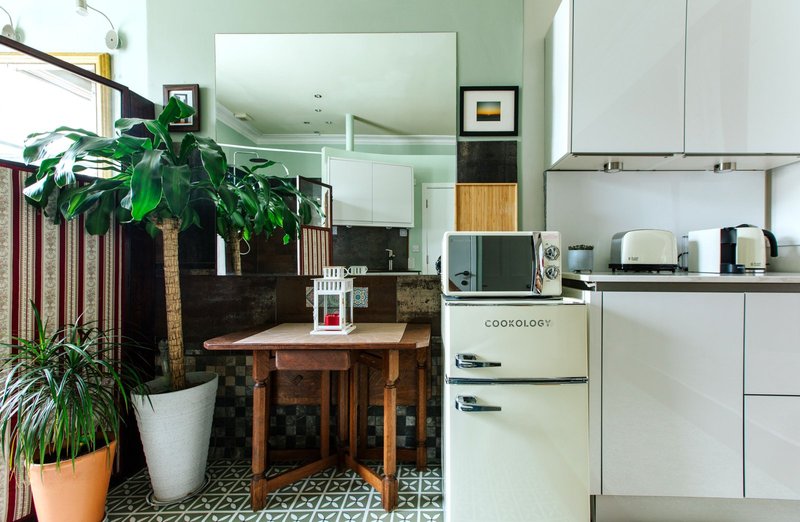 Open-plan kitchen and living area with cream retro fridge, wooden dining table, potted plants and modern cabinetry