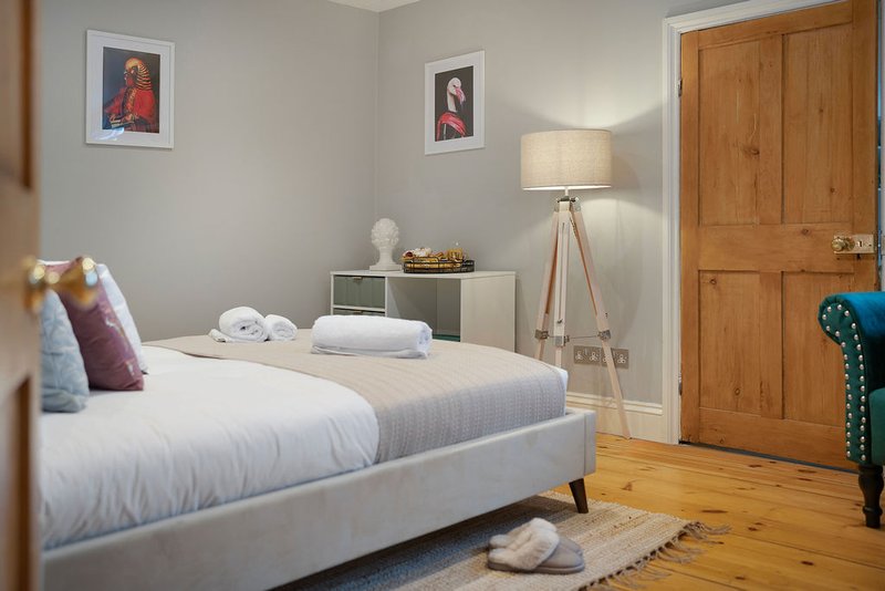 Modern bedroom with white bed, wooden wardrobe, tripod lamp, and framed wall art