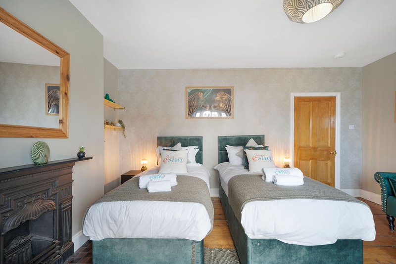 Twin bedroom with two beds, fireplace, wooden door, and wall art