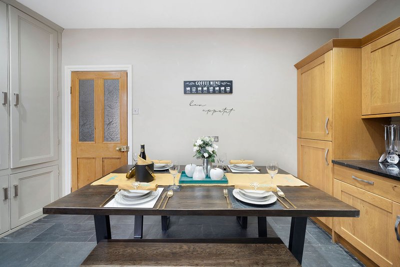 Modern dining room with dark table, wooden cabinetry, place settings, and wine bottle