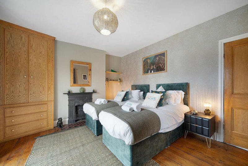 Spacious bedroom with double bed, wooden wardrobes, fireplace and hardwood flooring