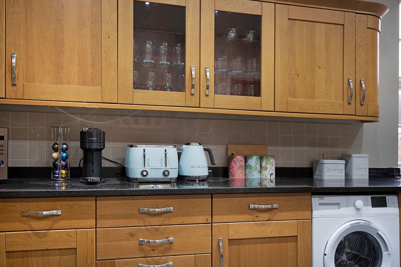 Kitchen with wooden cabinets, black countertop, appliances and decorative items on counter
