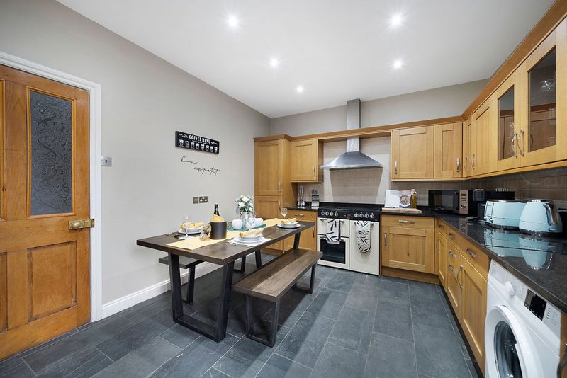 Modern kitchen with wooden cabinets, dining table, black countertops and appliances