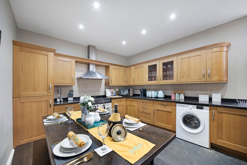 Modern kitchen with wooden cabinets, black countertops, dining island and integrated appliances