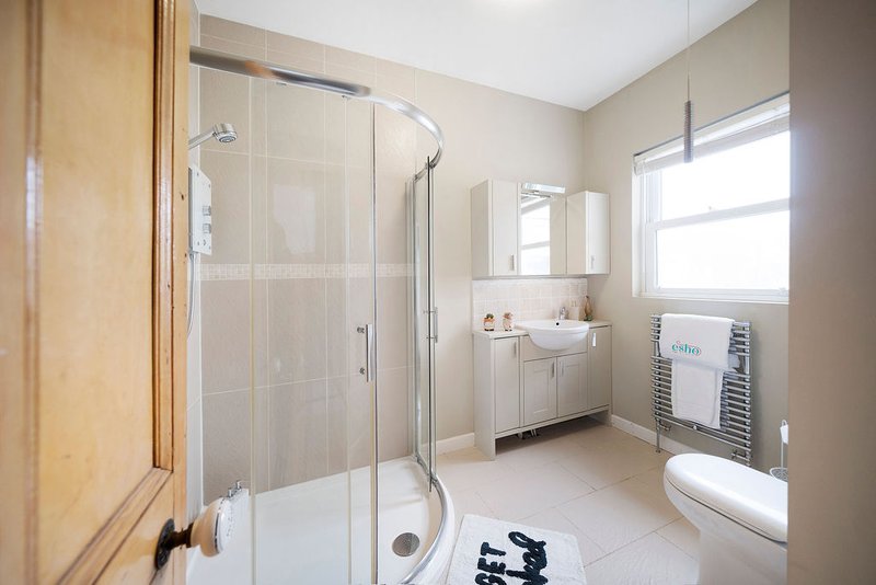 Modern bathroom with walk-in shower, white sink, toilet, and heated towel rail