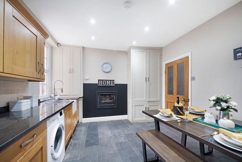 Open-plan kitchen and dining area with wooden cabinets, black countertops, dining table and fireplace