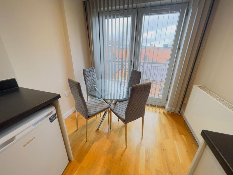 Modern dining area with round table, grey chairs, wooden floor and balcony doors