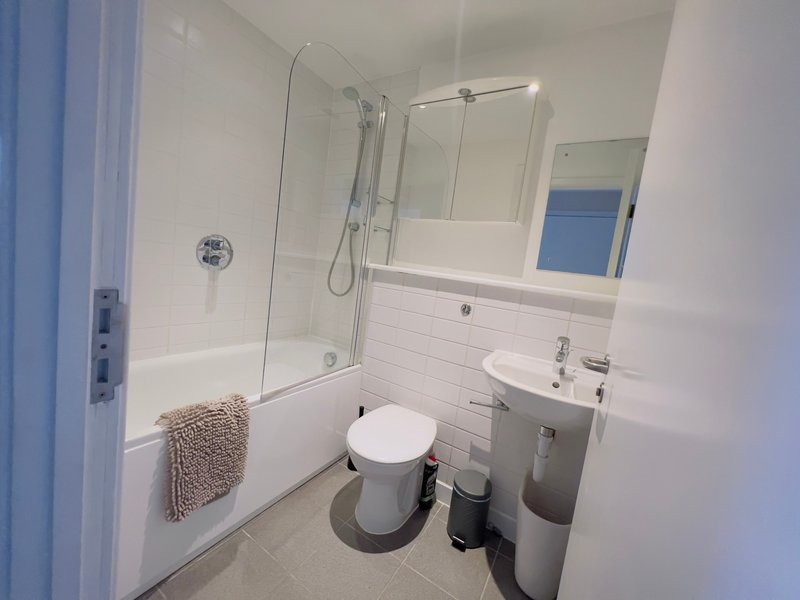 Modern bathroom with shower enclosure, toilet, sink, mirror and tiled walls