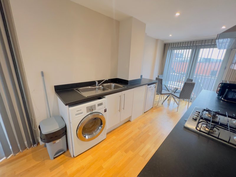 Modern kitchen with white cabinetry, black countertop, integrated washing machine and gas hob