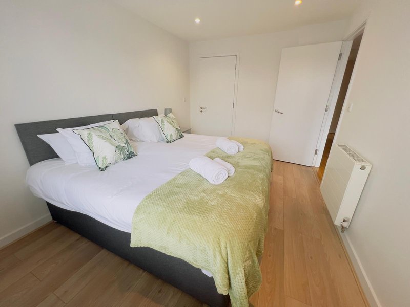 Bedroom with double bed, white and yellow bedding, wooden floor, and white doors